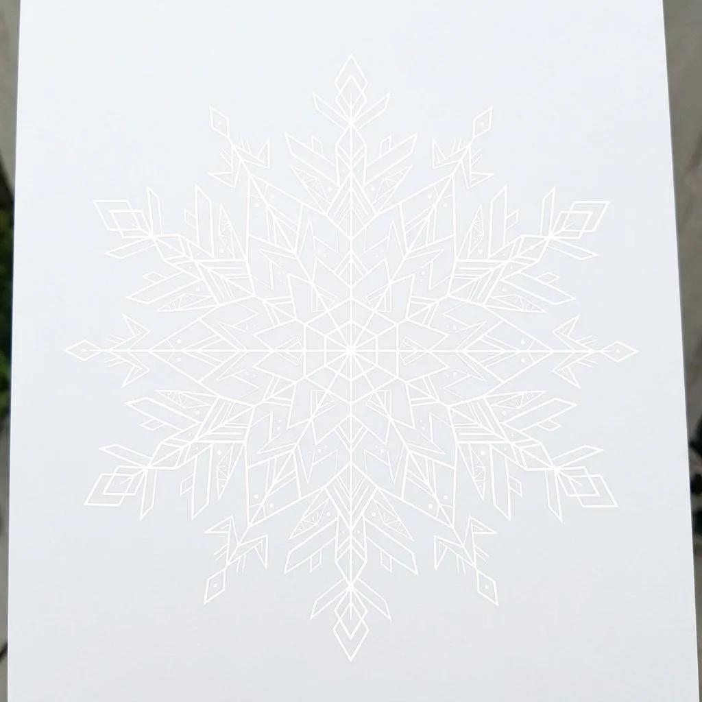 Fine-line white geometric snowflake tattoo design on a light background.